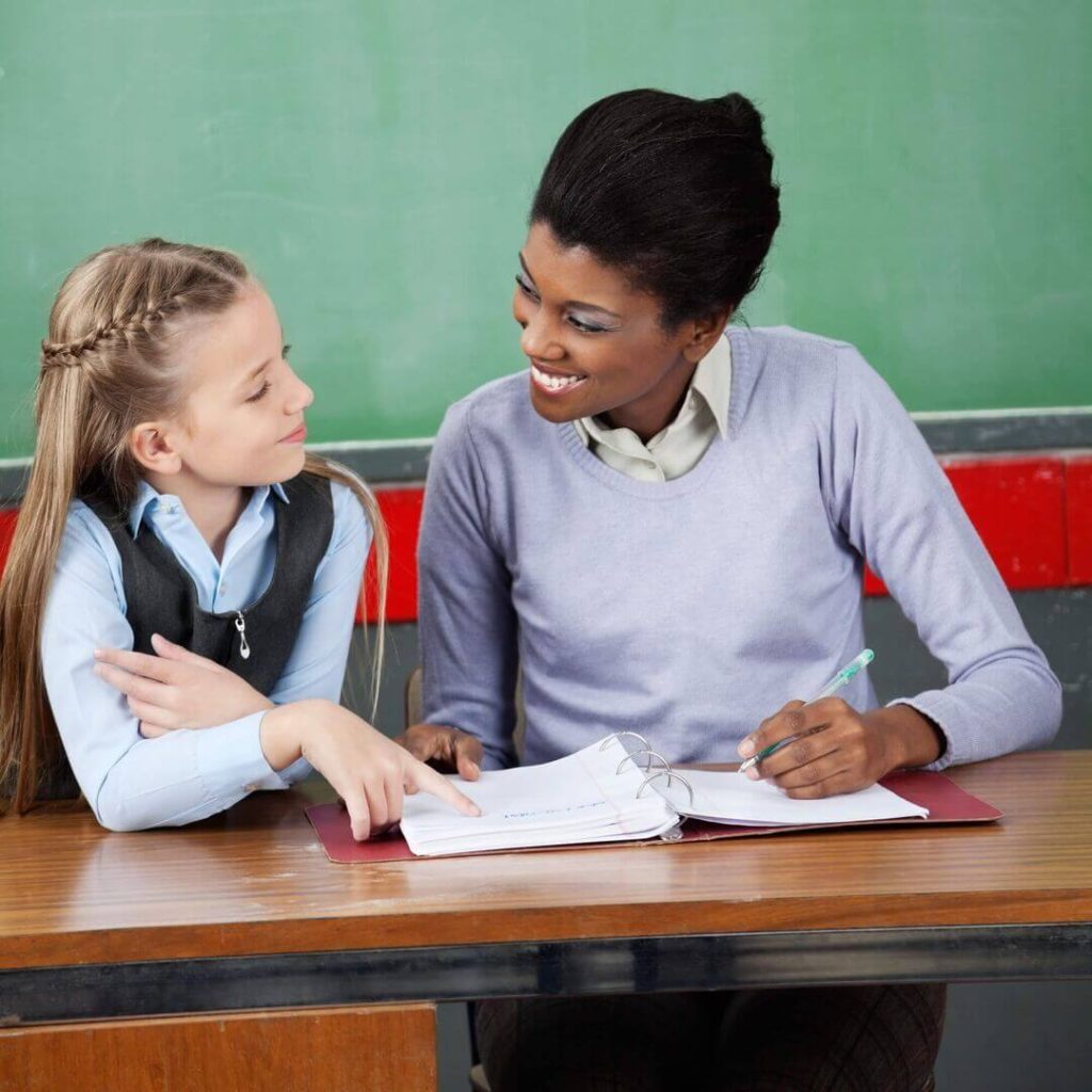 Teacher helping elementary student with data binder