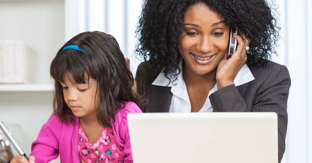 Teacher mom work on a computer with toddler by her side